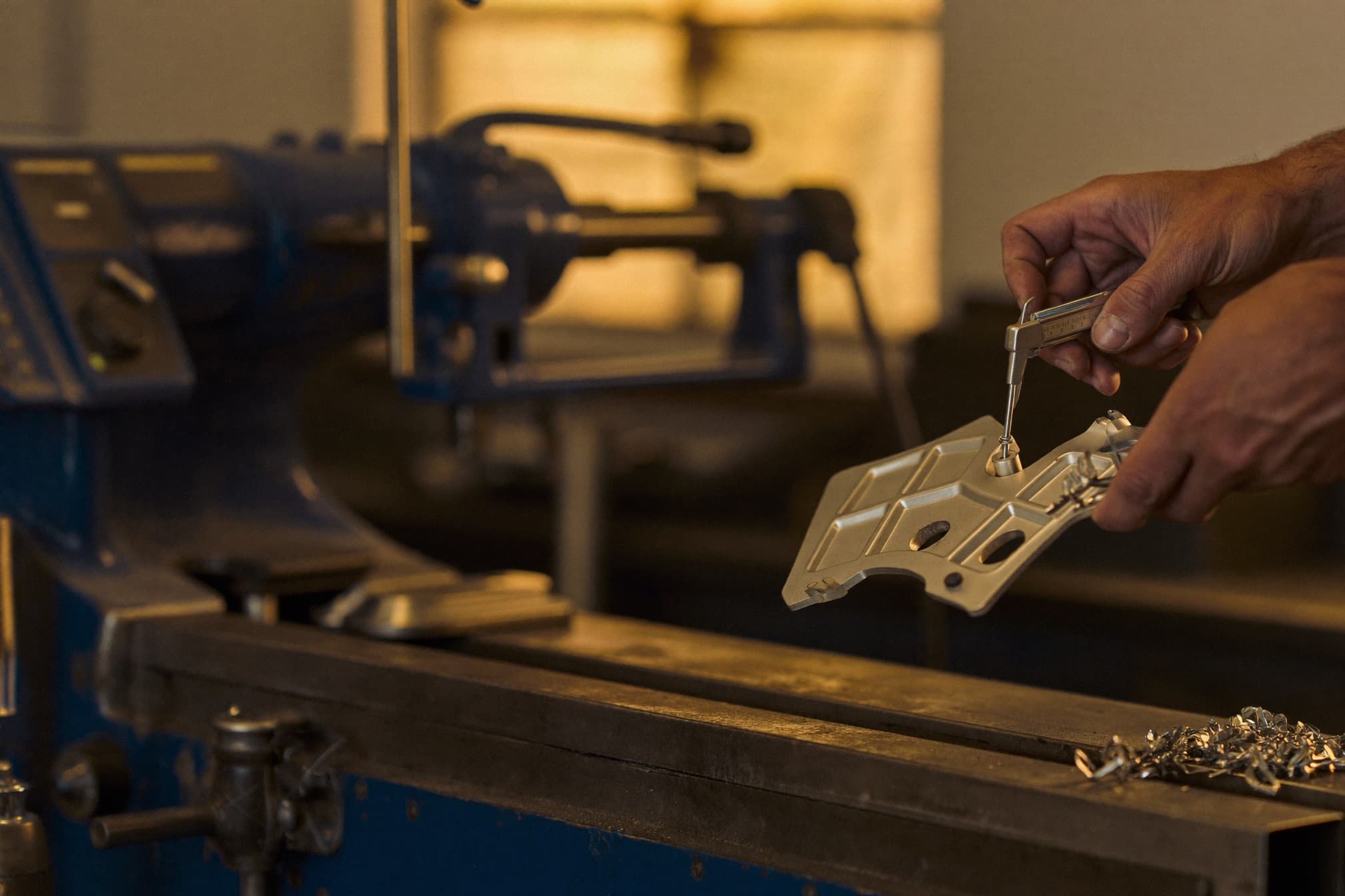 A machinist checking a finished part with a caliper.